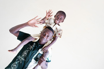 Skewed Shot of African black dad and son having fun in front of an isolated background smiling and laughing together as a diversity symbol