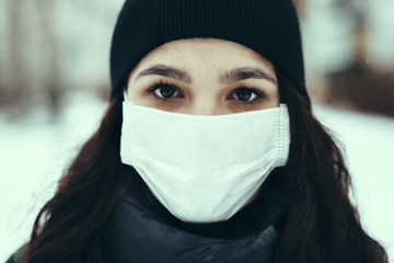 portrait of a sick Caucasian girl in a medical mask to protect against the virus during an epidemic