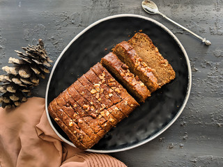 Carrot cake loaf made with oats and almonds, sliced on a black dish, top view. vegan, eggless cake. Healthy, diet, healthy lifestyle, nutrition, autumn, winter, moody, magazine, recipe book concepts.