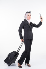 Muslim businesswoman in a hijab on a business trip with luggage isolated on white background. Suitable for cut out, manipulation or composite works for travel or business concept. Full length portrait