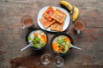 Congee with minced pork and slices of bread and delicious strawberry jam is a favorite breakfast for Thai people. on wood table texture. Top view