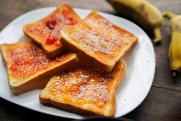 Plate with slices of bread and delicious strawberry jam on wooden table