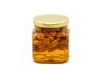 Glass jar with honey and almonds on white background