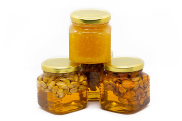 Pyramid of glass jars with honey with nuts and lemon on white background