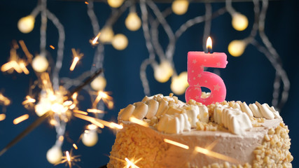Birthday cake with 5 number pink candles and burning sparkler on blue backgraund. Close-up