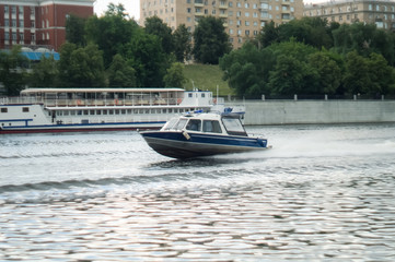 Fototapeta na wymiar motorboat racing through the river. Fast motion river police on a motorboat