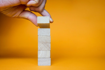 Hand arranging six wood blocks stacking on top with wooden table. Business concept for growth success process