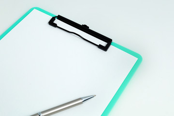 Close up green clipboard with blank white paper and pen