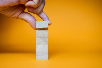 Hand arranging five wood blocks stacking on top with wooden table. Business concept for growth success process
