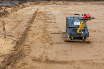 a building site there is a vibrator preparing the ground for foundations