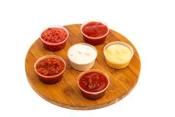 spicy meat seasonings ketchup, adjika, sauce in transparent plastic containers isolated