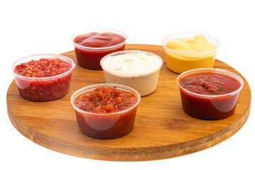 spicy meat seasonings ketchup, adjika, sauce in transparent plastic containers isolated