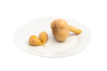 pickled garlic, whole and cloves on a white plate isolated