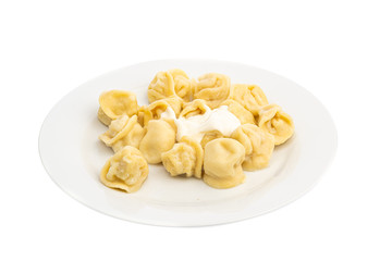 portion of boiled dumplings with white sour cream sauce on a white plate isolated