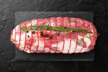 Raw roast beef with herbs tied with a rope with cooking ingredients, oil and spices .