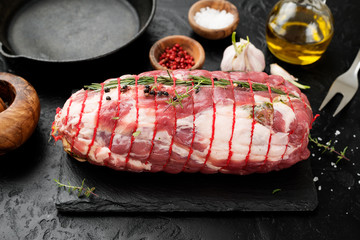 Raw roast beef with herbs tied with a rope with cooking ingredients, oil and spices .