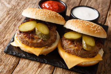 Homemade fried onion burgers with cheddar cheese and pickles close up. horizontal