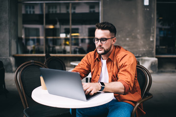Focused freelancer working on laptop while sitting in cafe