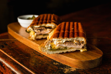 Traditional cuban sandwich with cheese, ham and fried pork, served on a wooden board - 321611167