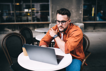 Confident freelancer working on laptop while sitting in cafe