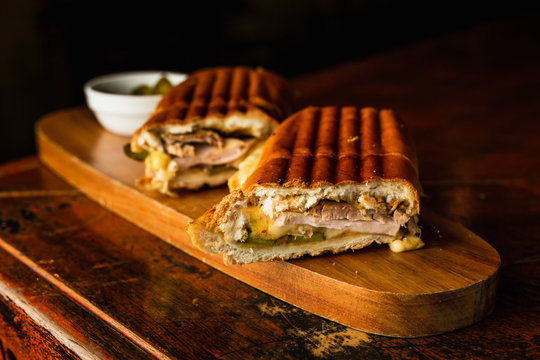 Traditional cuban sandwich with cheese, ham and fried pork, served on a wooden board