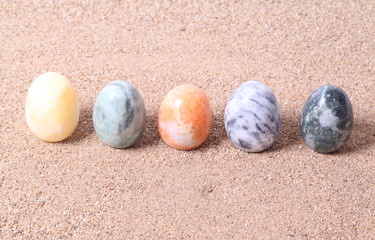 Colorful onyx egg on sand background.