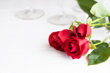 Beautiful red roses on white table interior of restaurant. Perfect gift for Saint Valentines day, anniversary o birthday .