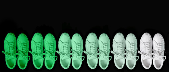 Short low brigt sneakers on a black background. Gradient of white to green