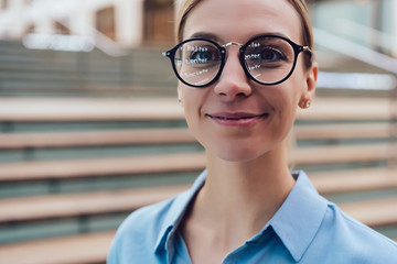 Portrait of Caucasian female of 20 years old looking at the camera. Smiling young woman wearing stylish optical eyewear with smart reflection . Women's eye glasses with diopters, vision correction.