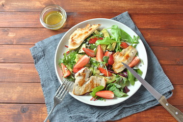 Chicken salad with avocado, strawberries, arugula, beet leaves and blue cheese Healthy food concept Avocado salad with chicken on wooden background