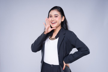 An attractive woman wearing business attire with gestures towards copyspace area isolated on grey. Good for manipulation works for technology, transportation, business or finance theme.