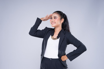 An attractive woman wearing business attire with gestures towards copyspace area isolated on grey....