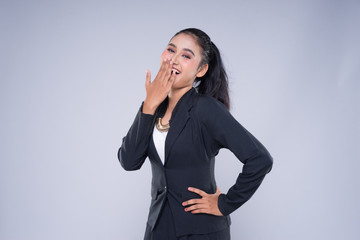 An attractive woman wearing business attire with gestures towards copyspace area isolated on grey....