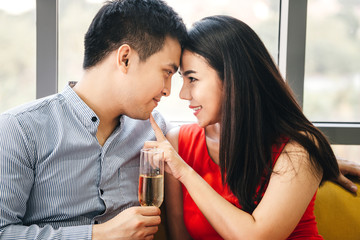Smile asian lover couple male hand hold a champagne. She touch finger on man face.