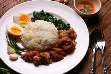 Stewed pork leg on rice on wooden table.Thai food