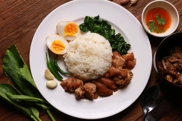 Stewed pork leg on rice on wooden table.Thai food