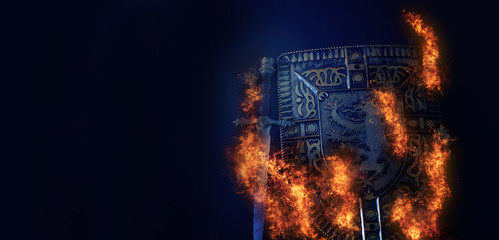 Fototapeta na wymiar photo of shield knight armor and sword in fire flames over dark background. Medieval period concept