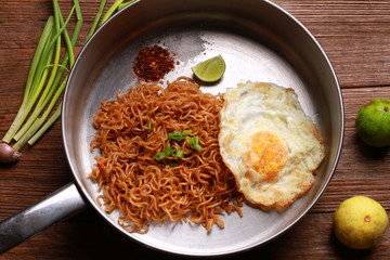 Mi goreng or mee goreng mamak, Indonesian and Malaysian cuisine, spicy fried noodles on wooden table.