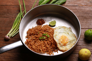 Mi goreng or mee goreng mamak, Indonesian and Malaysian cuisine, spicy fried noodles on wooden table.