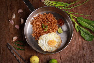 Mi goreng or mee goreng mamak, Indonesian and Malaysian cuisine, spicy fried noodles on wooden table.