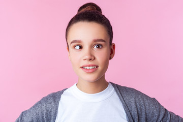 Portrait of adorable funny brunette teen girl with bun hairstyle in casual clothes fooling around...