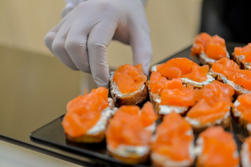 waiter lays out salmon canapes for catering
