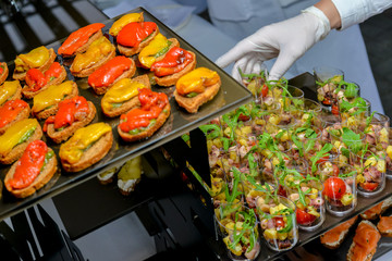 the waiter lays out on a catering canapes with baked sweet pepper
