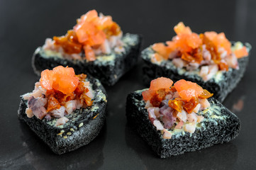 bruschettas on a black bun with salmon from the chef on a black background