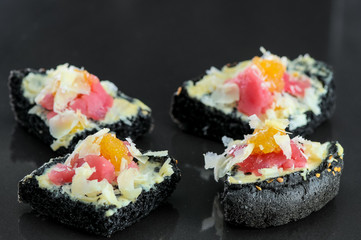 bruschettas on a black bun with tuna and cheese from the chef on a black background