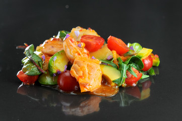 avacado salmon salad and tomatoes on black glossy background