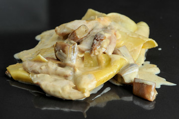 pancakes with mushrooms in a creamy sauce on a black glossy background
