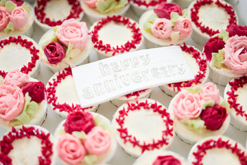 Beautiful cup cakes flowers from butter cream, in red and pink colour with Happy Anniversary text on fondant.