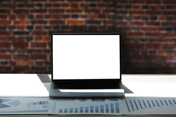 Laptop with blank screen on table interior, man at his workplace using technology.