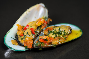 mussels with vegetables in sauce on a black background